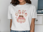 White t-shirt with a pink paw print design saying "Dog Mom Era".