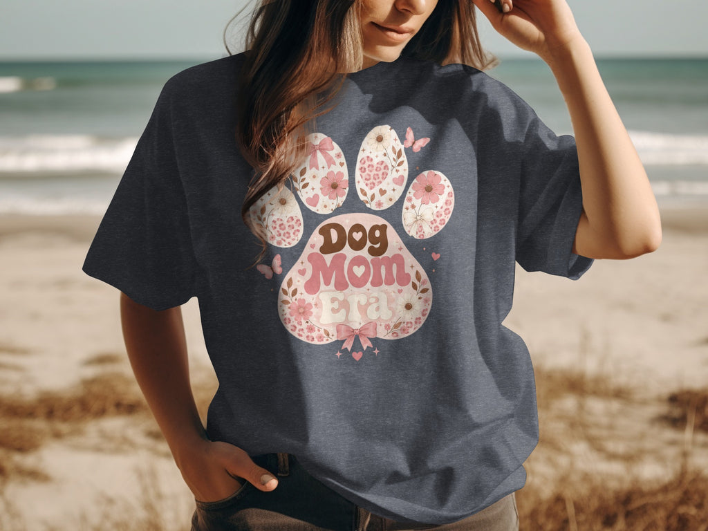 Dog Mom Era graphic on a dark t-shirt with a beach background.