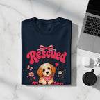 Dark blue t-shirt with a rescued puppy design, pink text "Rescued" and flowers.