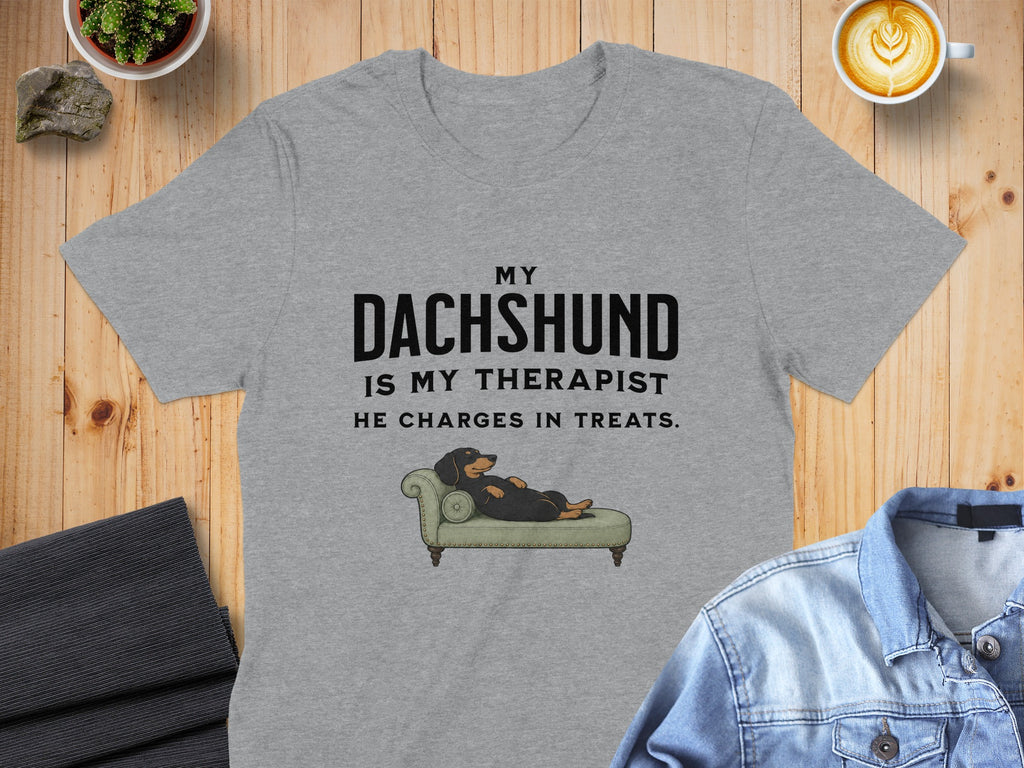 Grey t-shirt with text "MY DACHSHUND IS MY THERAPIST. HE CHARGES IN TREATS." and illustration.