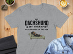Grey t-shirt with text "MY DACHSHUND IS MY THERAPIST. HE CHARGES IN TREATS." and illustration.