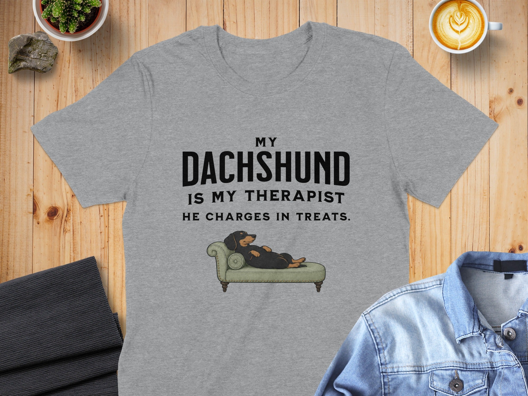 Grey t-shirt with text "MY DACHSHUND IS MY THERAPIST. HE CHARGES IN TREATS." and illustration.
