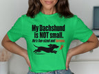 Green t-shirt with black text "My Dachshund is NOT small. He's fun-sized and furious" and a running dachshund.