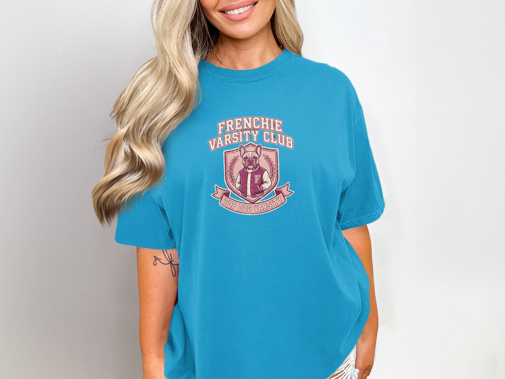 Frenchie Varsity Club logo on a teal t-shirt.