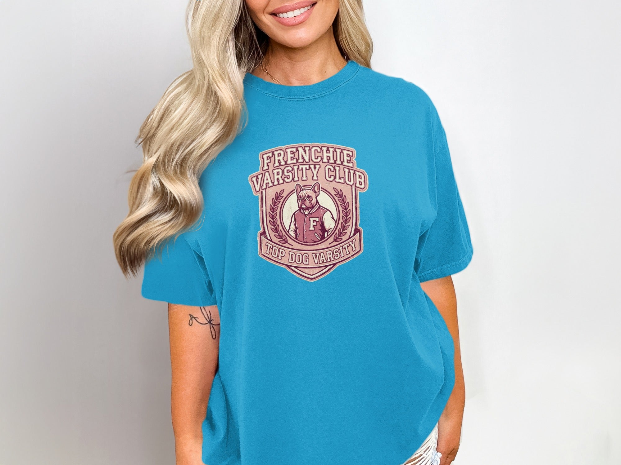 Frenchie Varsity Club logo with shield and "F" on a turquoise t-shirt.