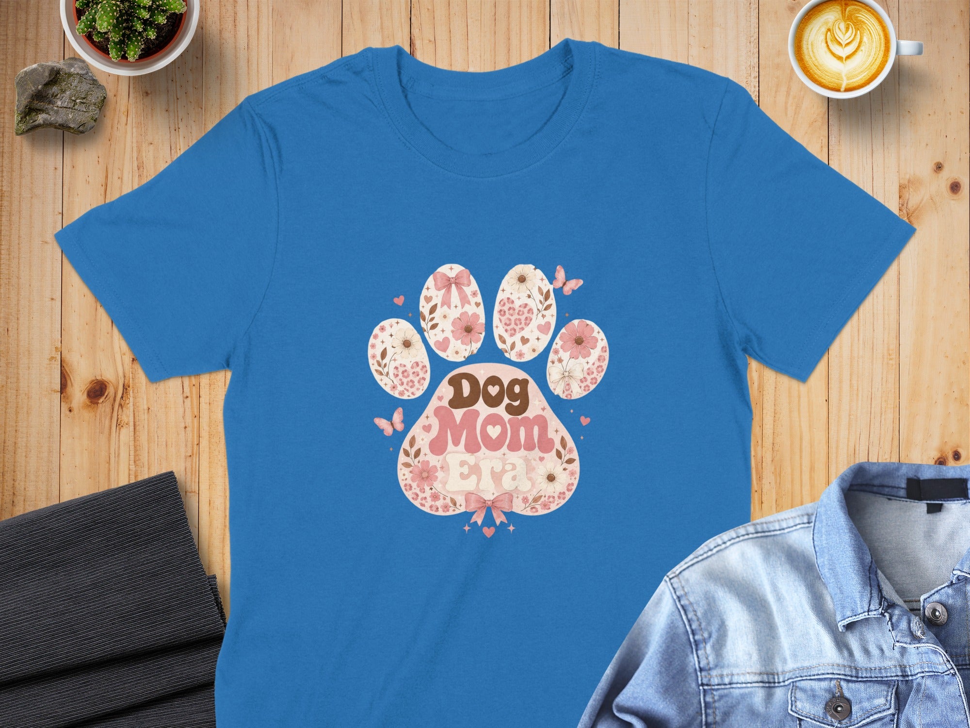 Blue t-shirt with a pink dog paw print design featuring floral and butterfly motifs.