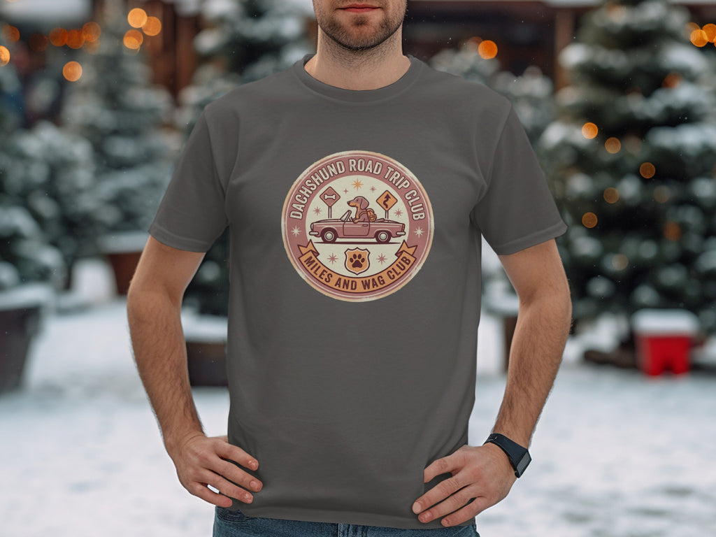 Grey t-shirt with a round patch featuring a dachshund in a car and the text "Dachshund Road Trip Club."